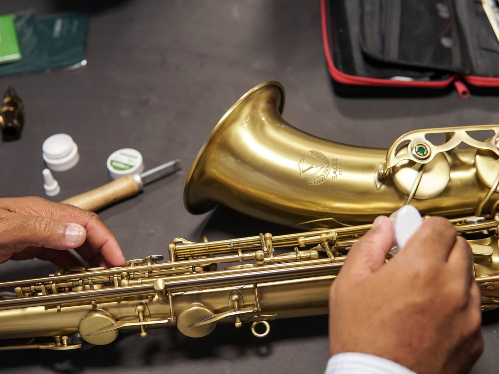 Reinigung eines zerlegten Saxophons mit einer weichen Bürste in der Werkstatt